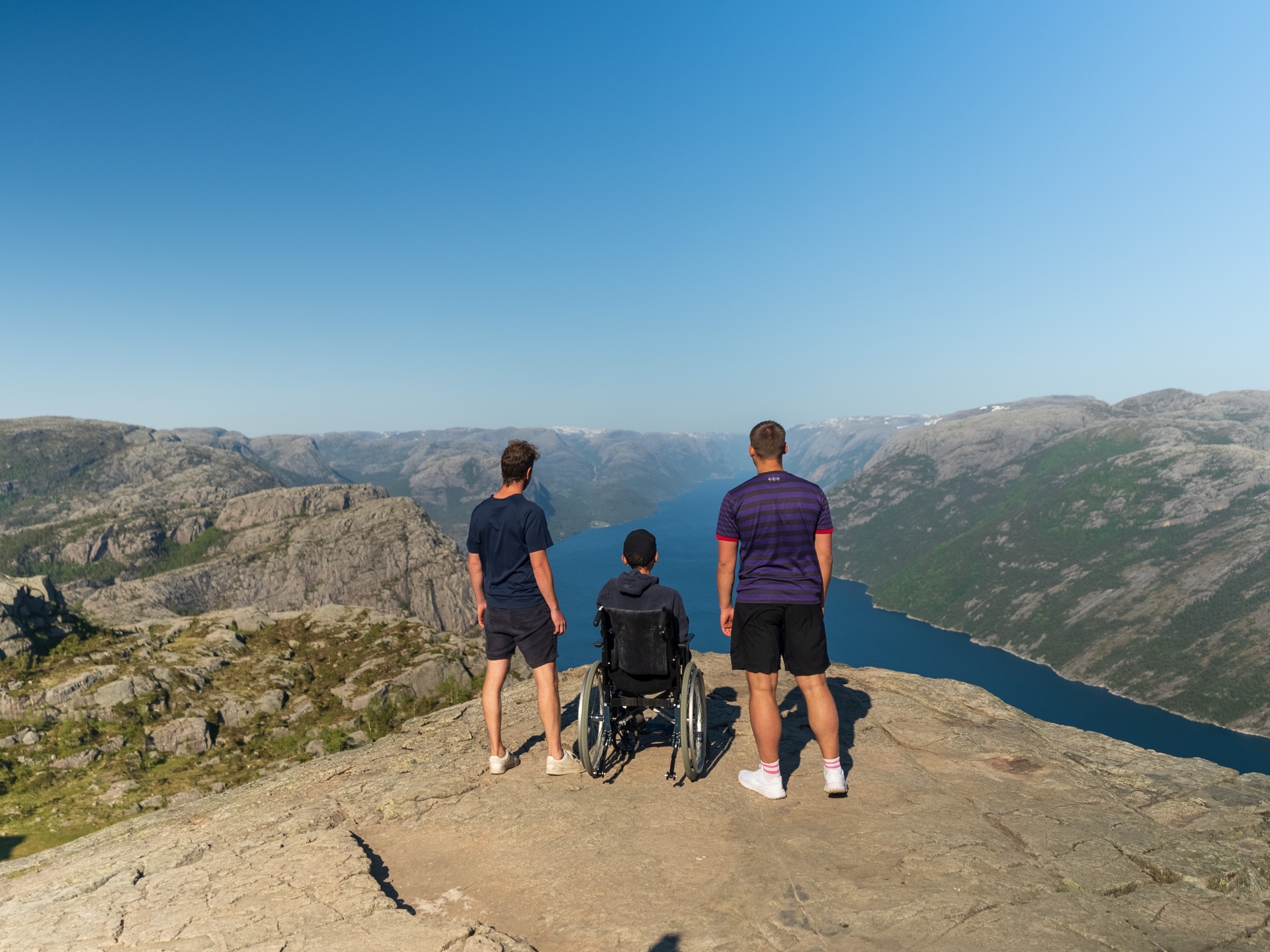 Tre venner ser utover Lysefjorden – en av dem i rullestol.
